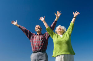 Una pareja levantando alegremente los brazos al cielo.